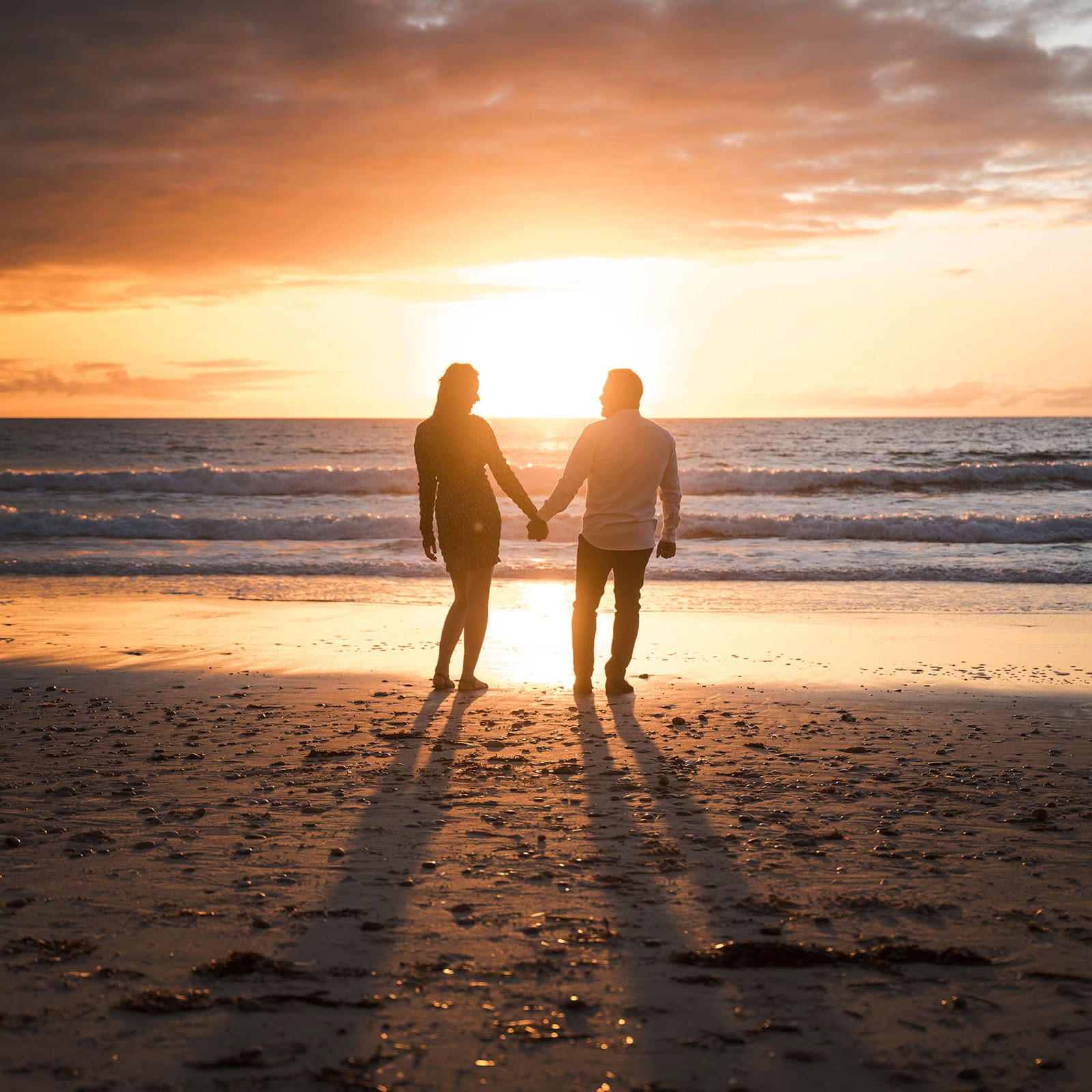 Manos entrelazadas de una pareja al atardecer